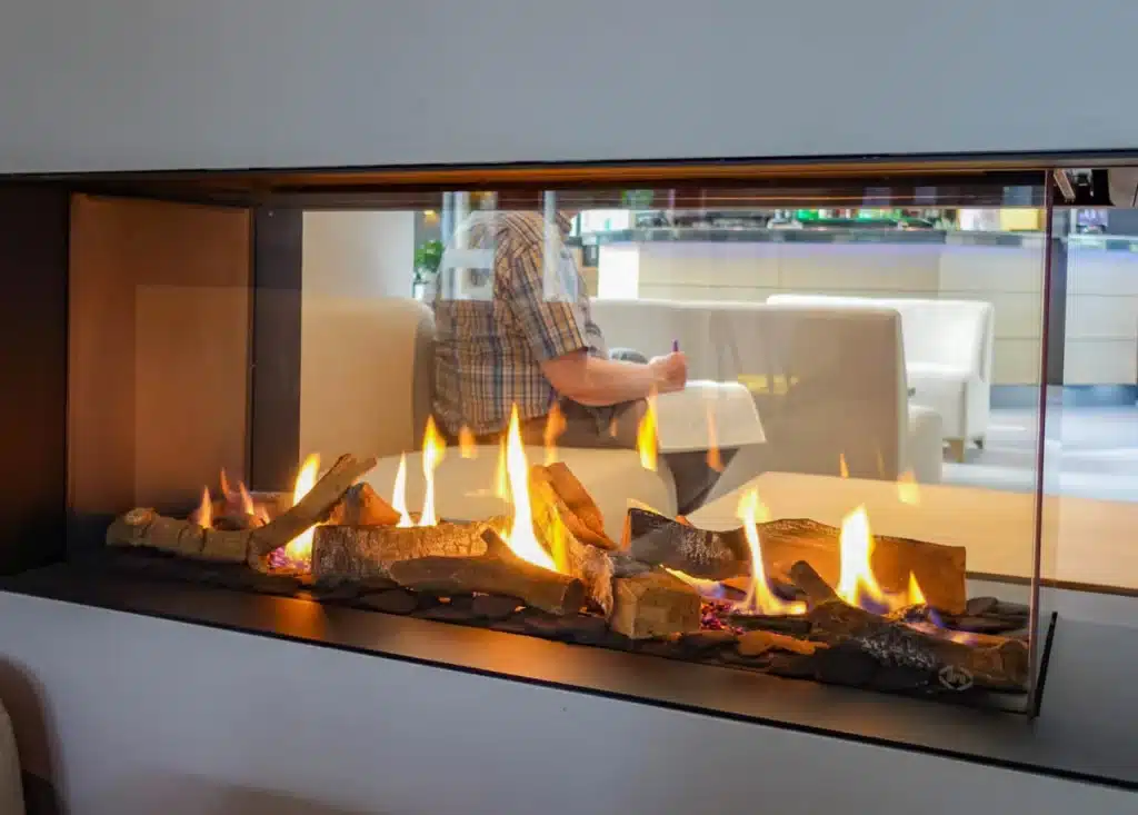 Foyer vitré sur trois côtés, flammes sur lit de bûches