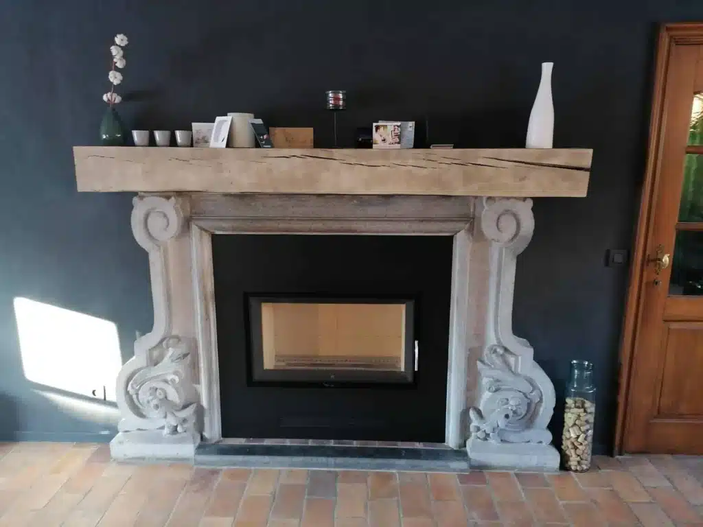 Insert à bois encastré dans une cheminée en pierre sculptée